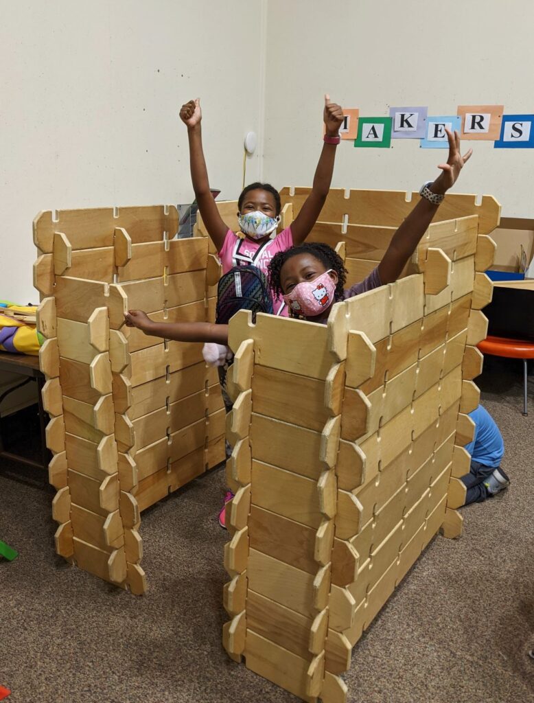 Two children stand in a fort constructed in the library's makerspace