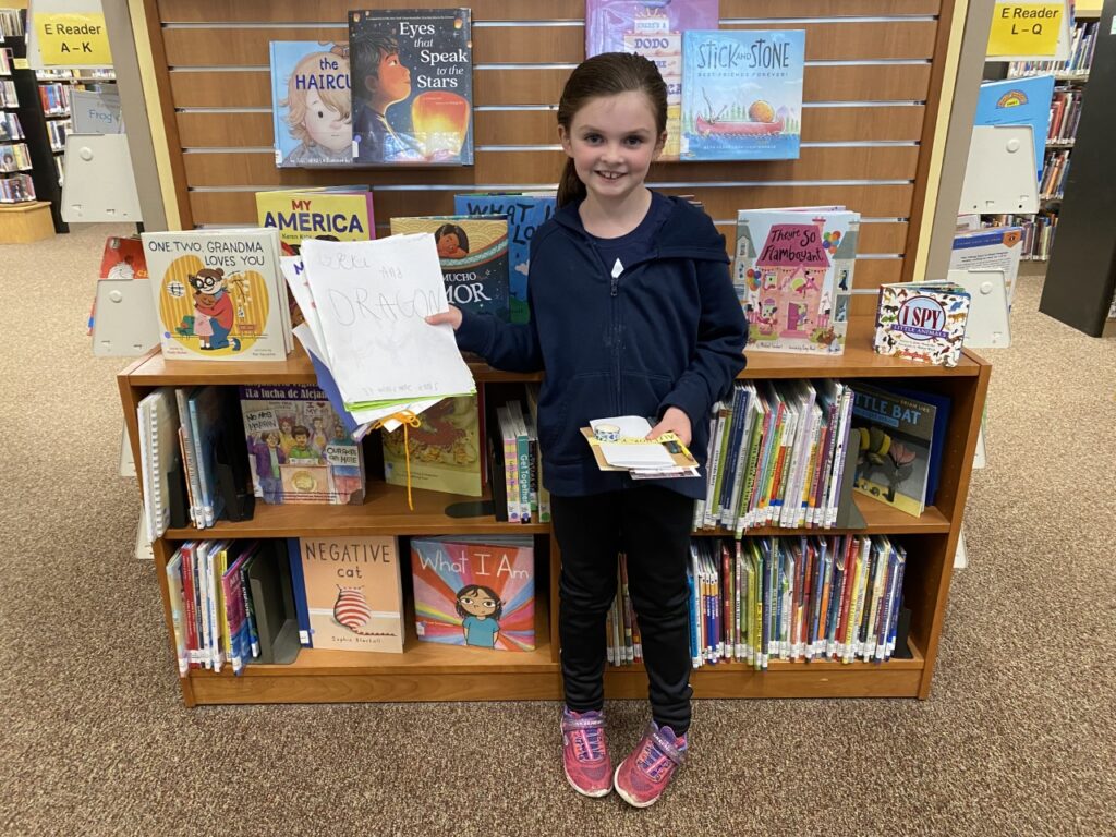 Mollie, age 7, stands with some of her recently written books