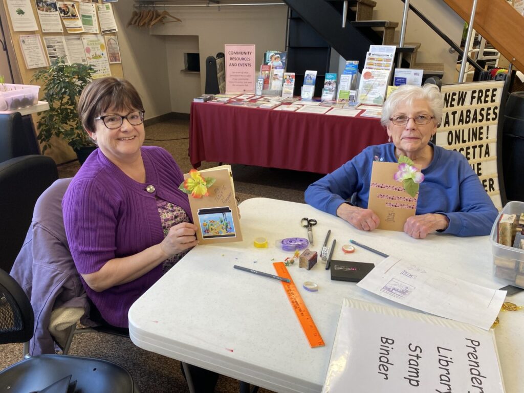 Two people sit at a table displaying their decorated journals